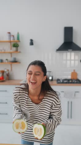 mujer sosteniendo un pomelo cortado en la cocina