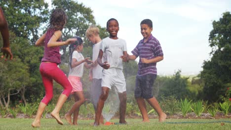 niños jugando con rociadores de jardín
