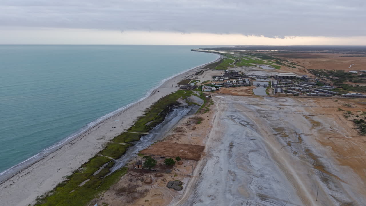 Drohnenvideo, das La Guajiras atemberaubende Küste in Kolumbien einfängt. Der Blick von oben auf weite Sandstrände, den blauen Ozean und zerklüftetes Gelände trägt zur ruhigen Atmosphäre bei.