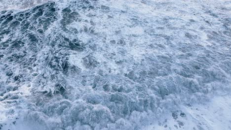 Vik-Black-beach-drone-flying-towards-the-sea-and-panning-down-close-up-waves