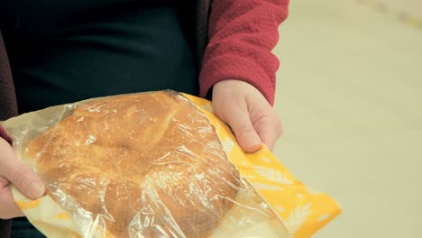 women hands hold round wheat bread