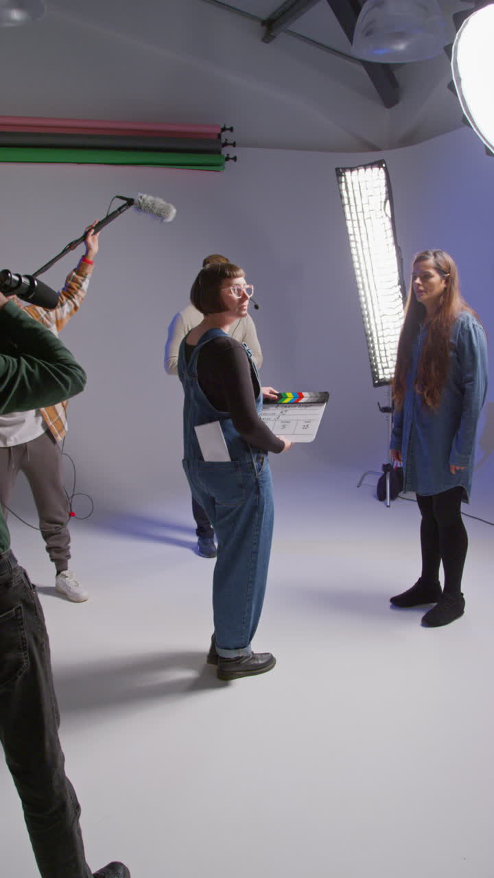 video vertical de asistente femenina usando clapperboard como actores filman una película o video en el estudio con el equipo de filmación y el director filmado en tiempo real 2