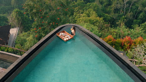 vista superior mujer desayunando en la piscina disfrutando de comida exótica en el spa de un hotel de lujo con vista a la selva tropical