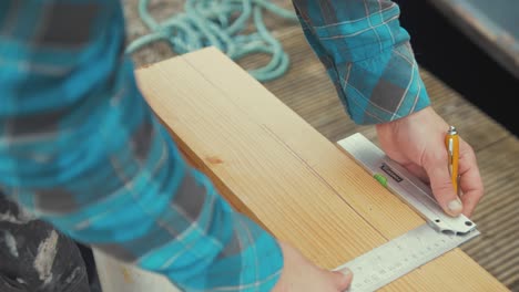 un carpintero masculino ordena líneas en una tabla de madera