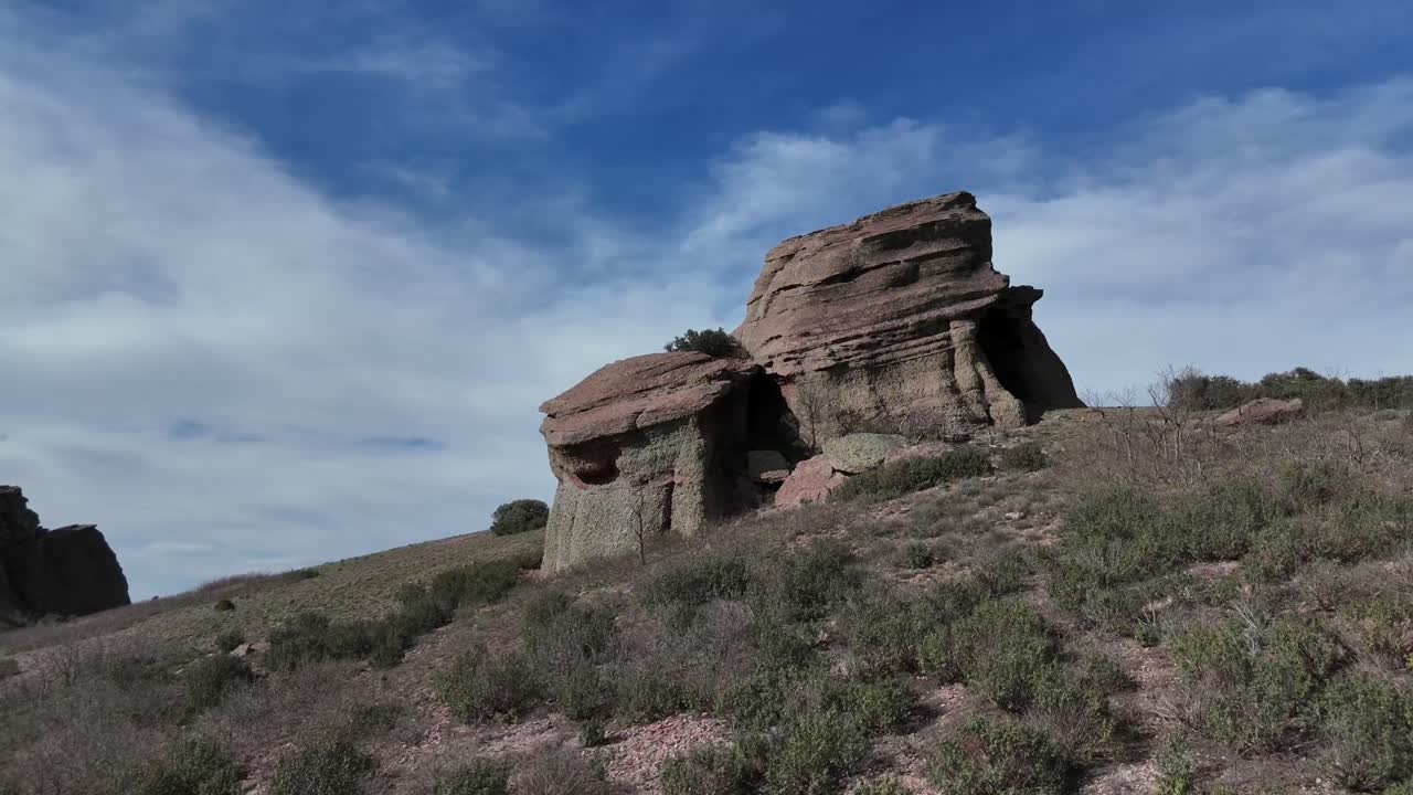 vista aérea de un avión no tripulado volando hacia adelante de un enigmático paisaje de piedra arenisca roja en guadalajara, españa, en una tarde soleada con un cielo azul