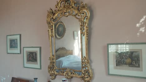 slow rotating shot of a gilt-edged mirror hanging on a wall beside picture frames