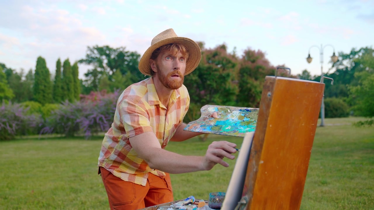 Mannlig kunstner maler på staffeli utendørs i en grønn park