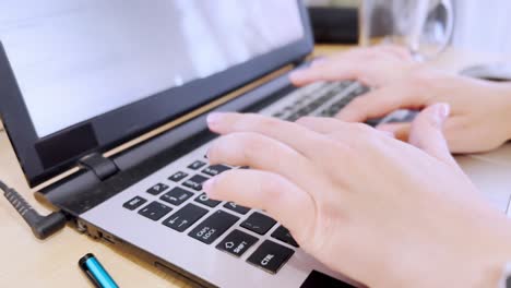 side view of female developer's hands typing code on a laptop keyboard