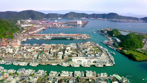 Vista-Aérea-Del-Puerto-De-Suao-Con-Muchos-Barcos-De-Atraque-Y-Casas-En-La-Isla---Hermoso-Paisaje-Montañoso-En-El-Fondo