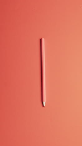 vertical video of overhead view of pink crayon with copy space on pink background, in slow motion