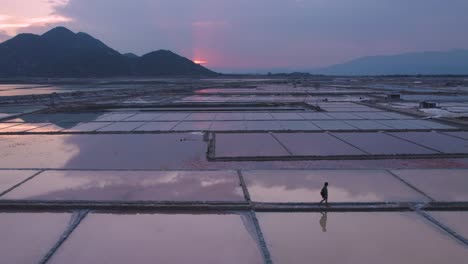 Silhouette-of-explorer-walking-through-vast-endless-salt-fields-during-golden-hour-in-Phan-Rang,-Vietnam