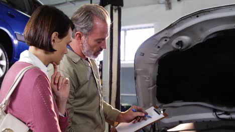 mechanic showing customer the problem with car