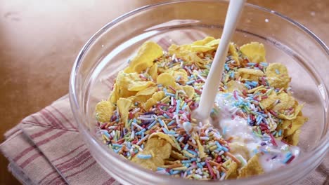 flocos de maíz amarillos crujientes en el cuenco para la mañana un delicioso desayuno con leche. cámara lenta con toma de seguimiento de rotación.