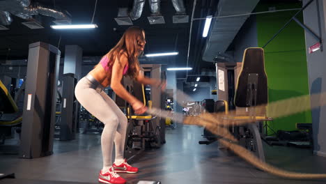 muscular fitness woman trains triceps with two cables by her hands on the background of a new fitness center. fit woman exercise with cable crossover in gym.