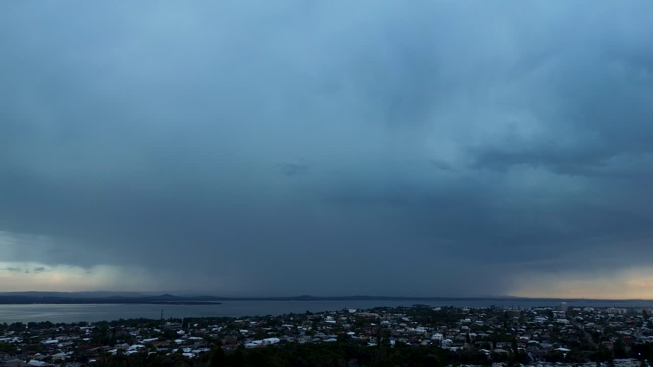 Drone aerial landscape of lightning strikes and zaps from looming storm clouds over suburban town and rural housing on a rainy morning in Long Jetty Central Coast Australia weather nature environment