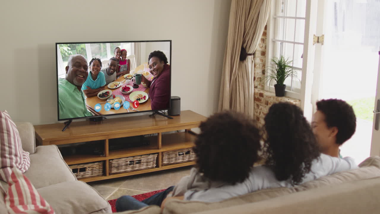 Famiglia afroamericana che fa una videochiamata in TV mentre è seduta sul divano a casa