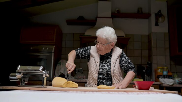 mujer de edad amasar la masa en la cocina