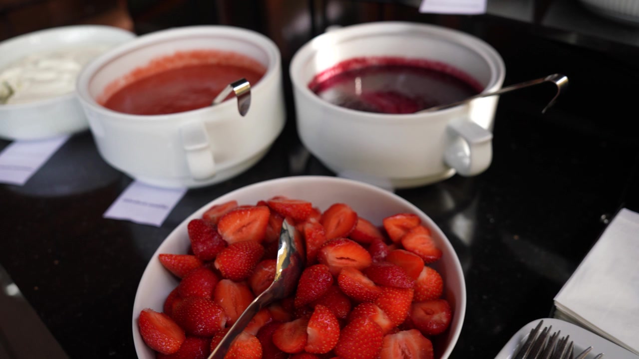 Close-up view of a buffet restaurant display featuring fresh strawberries and bowls of jam.