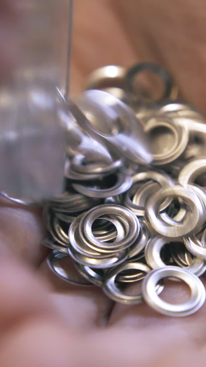 CU: Professional designer pours eyelet details on hand against green cutting board in workshop extreme close view