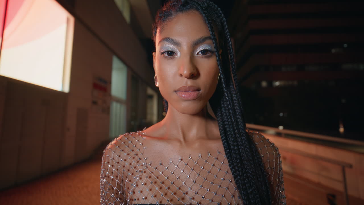 творческая макияжная дама смотрит на камеру в ночной портрет. брюнетка позирует