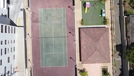 video de un dron sobre una cancha de tenis en una zona residencial, estilo de vida deportivo