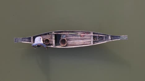 lonely man fishing in traditional wooden fishing boat in asia, top down view