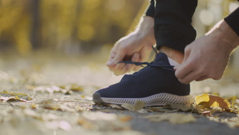 man tying his running shoes in a park