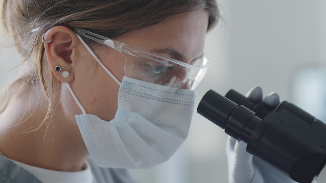 Trabajadora de laboratorio usando un microscopio
