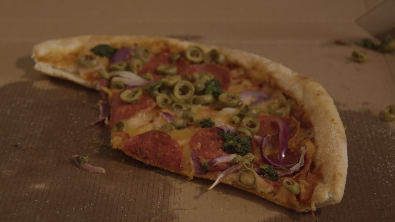 페퍼로니, 올리브, 양파를 얹은 부분적으로 먹은 피자 팬