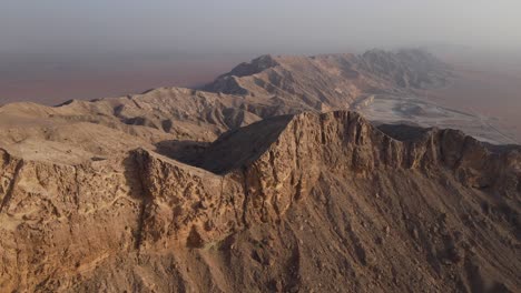 2021:-Rear-Drone-view-of-UAE's-Mleiha-Mountain-range-landscape,-Sharjah's-Mleiha-desert,-Mountains-in-the-United-Arab-Emirates,-4k-footage