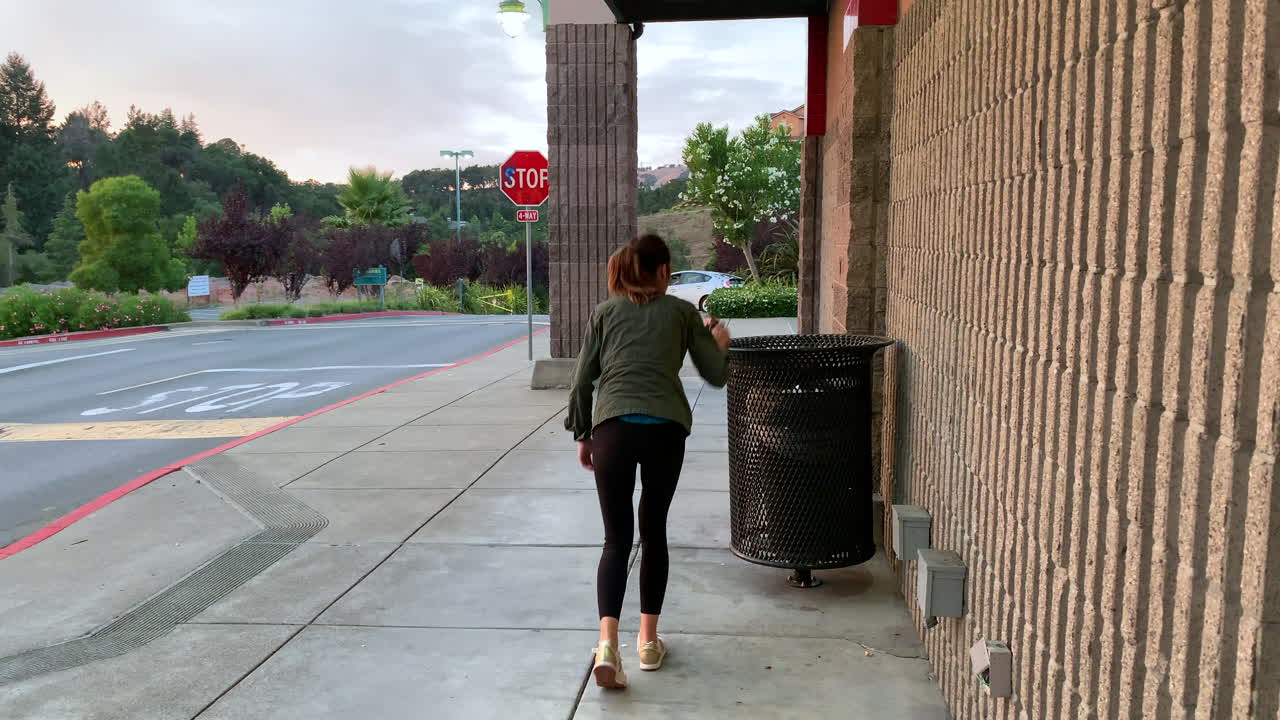 Woman walking by and picking up random trash on the ground to dispose of it