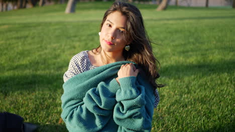 close up of a pretty hispanic woman trying to get warm and cozy with her sweater in cold season windy weather