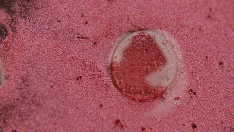 una gota de agua en una sustancia roja con partículas brillantes