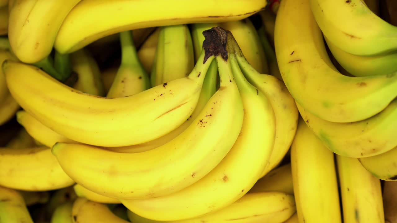 4k 배경에서 회전하는 노란 바나나 클로즈업이 구매자를 위해 저장되어 있습니다.