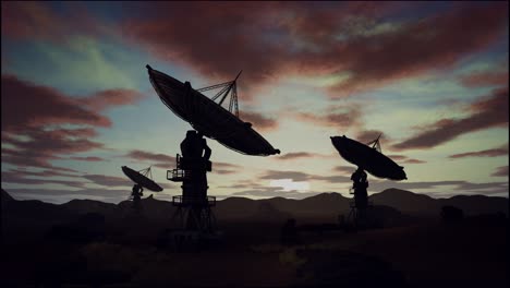 satellite dishes on field against cloudy sky during sunset