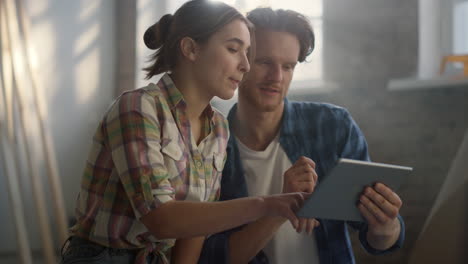 Smiling-couple-searching-pictures-with-house-interiors-on-tablet-indoors.