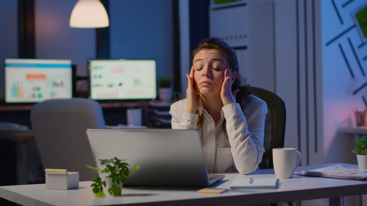 Donna d'affari stressata che soffre di mal di testa al lavoro mentre fa gli straordinari
