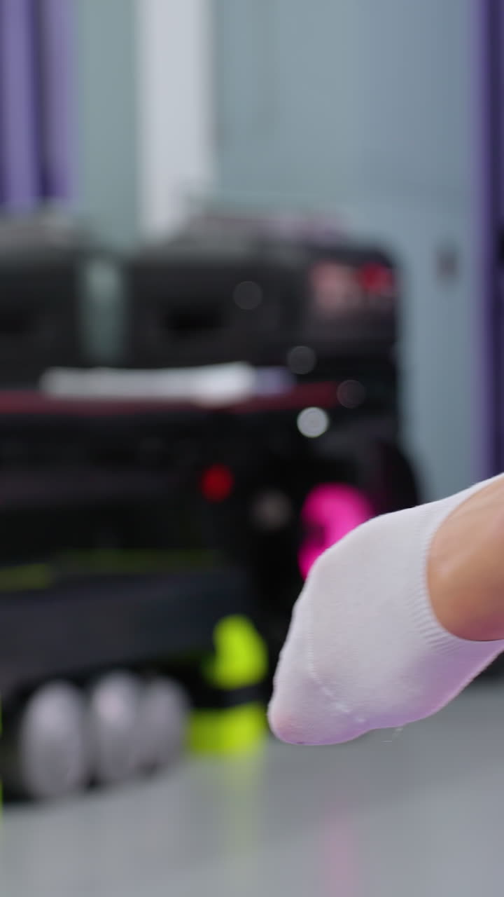 primer plano de estiramiento de las piernas durante el entrenamiento en el gimnasio, el fondo presenta varios equipos de fitness, incluida una caja de música que emite luces de colores parpadeantes