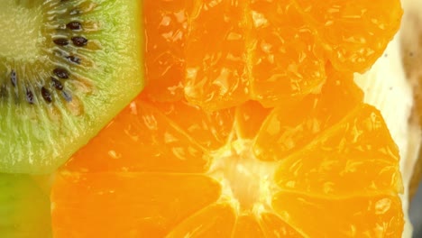 macro cercana del borde de una tarta de frutas casera que incluye crema de vainilla con rodajas de naranja y kiwi