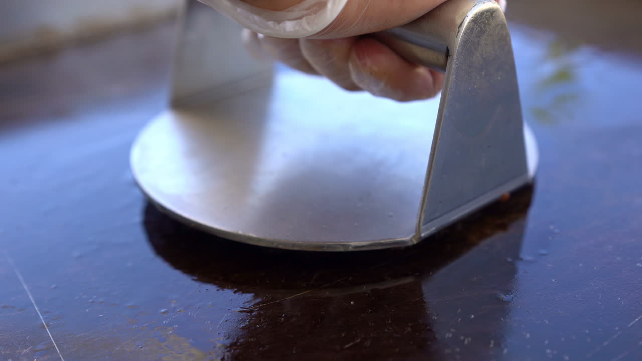 셰프가 다진 고기 조각을 그릴 클로즈 샷에 눌러줍니다.