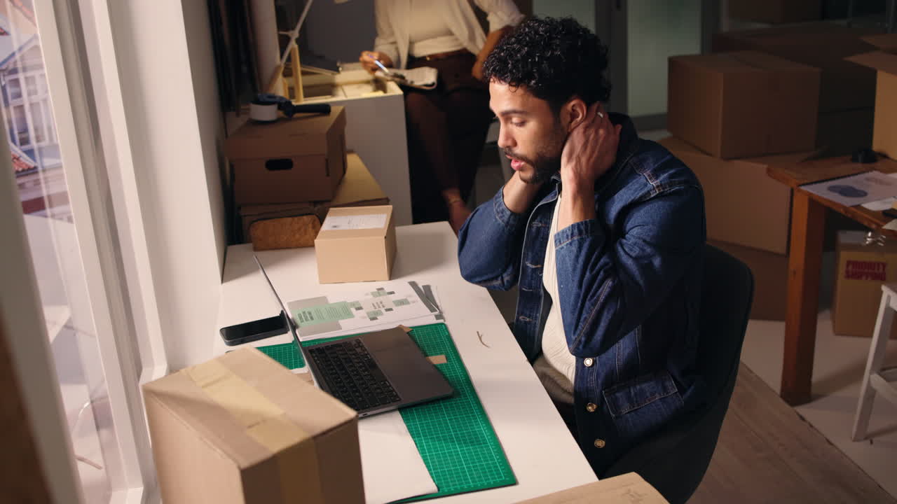 Stressed Young Man Working Late on Laptop in Small Business Office