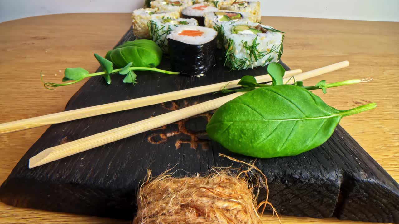 Assorted Sushi Rolls With Greens and Wasabi Served on Black Wooden Platter in Probe Lens Dolly out
