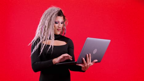 drag queen using a laptop on a red background