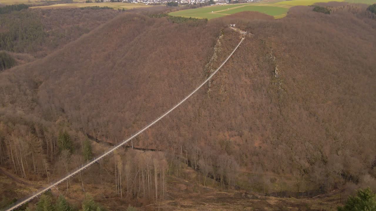 largo puente colgante que cuelga sobre un cañón marrón profundo en un día de invierno nublado