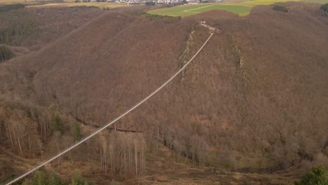 Largo-Puente-Colgante-Que-Cuelga-Sobre-Un-Cañón-Marrón-Profundo-En-Un-Día-De-Invierno-Nublado