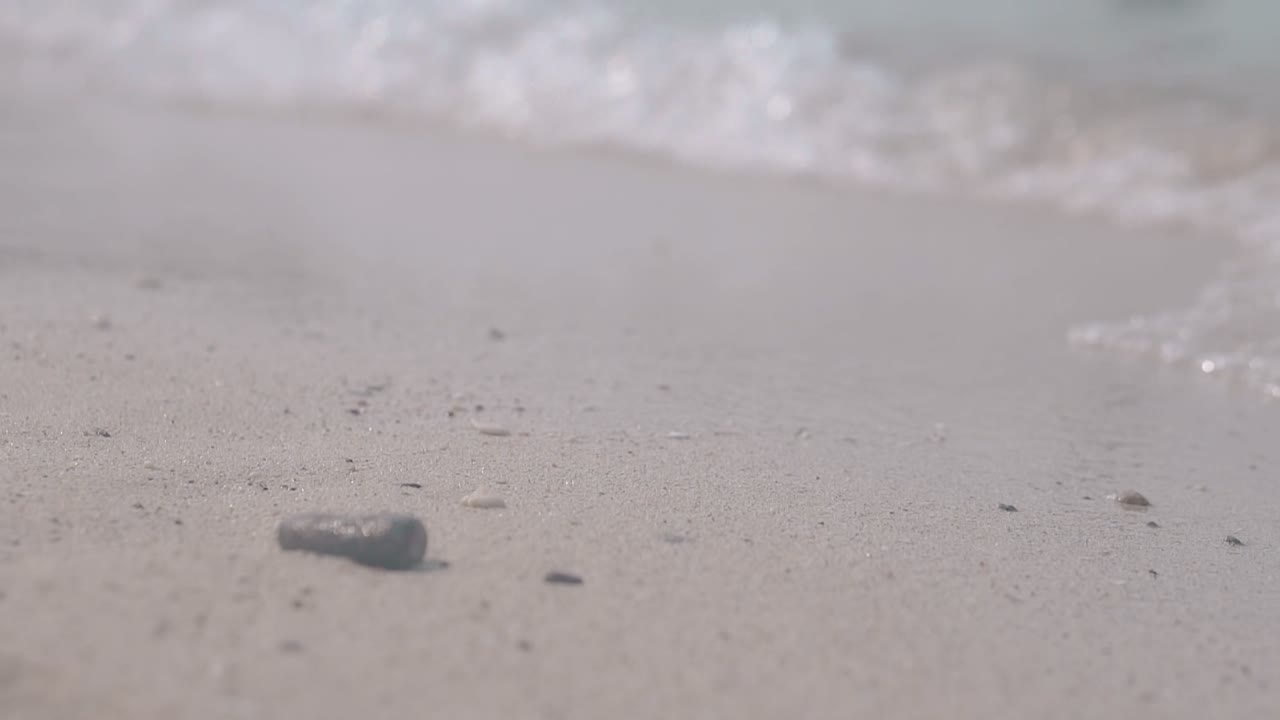 돌은 전면에 놓여 있고 평온한 투명한 파도가 굴러갑니다.