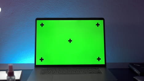 zoom-in-to-chroma-key-green-screen-laptop-on-desk-in-night-room