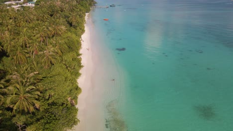 panorama de la isla maldiva con una costa en la que se encuentran un muelle y un lugar de amarre en aguas turquesas