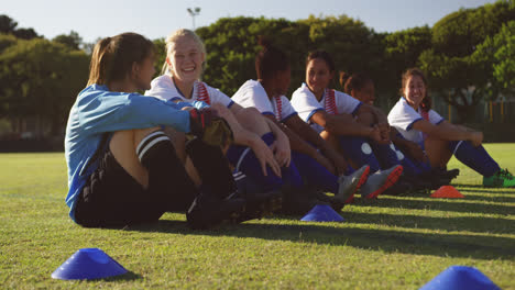 female soccer team sitting on the ground while talking on soccer field. 4k