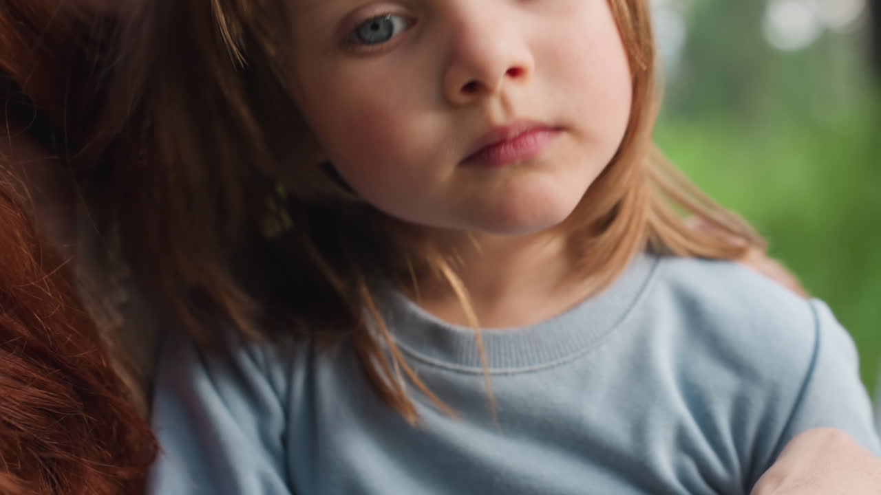 Close up tender moment showing mother kissing toddler on cheek to comfort her, expressing deep love, empathy, and affection, as child looks calm and reflective, surrounded by natural soft daylight